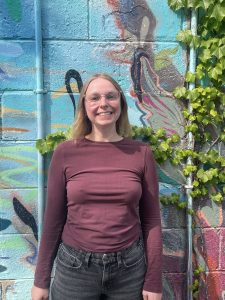 A photo of Jennie in front of a blue mural.